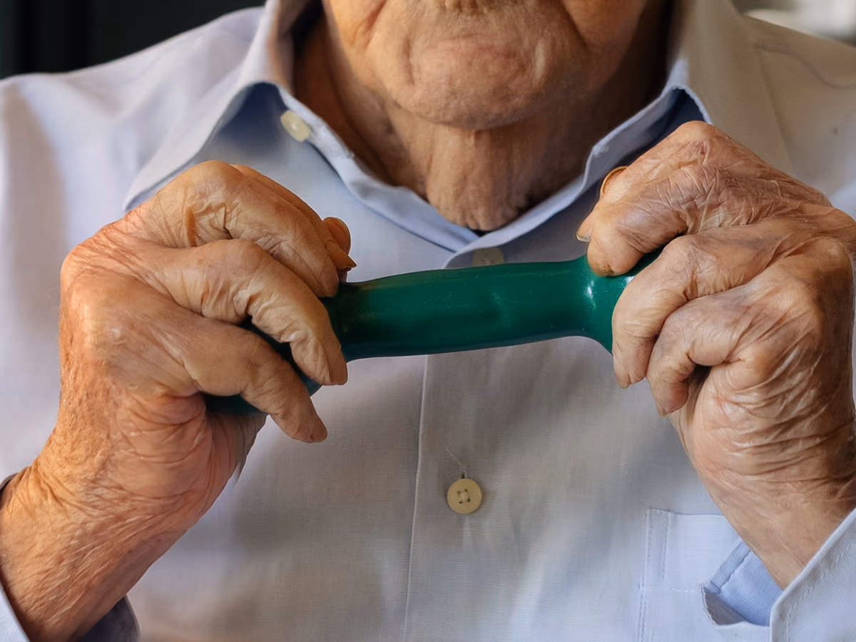 Mãos de fisioterapeuta apoiam com cuidado a mão de uma paciente