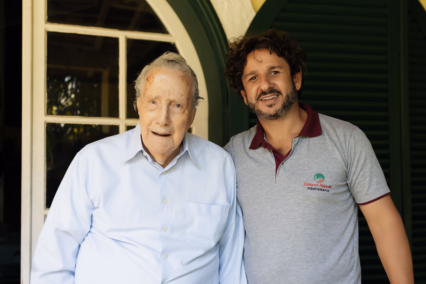 Haiquel Abjaude ao lado de uma pessoa acompanhada em atendimento domiciliar