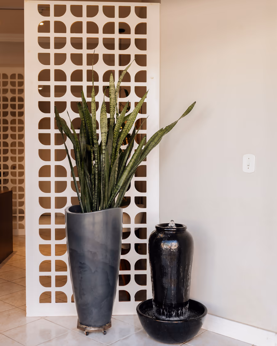 Cobogó branco e plantas que integram a arquitetura interna da clínica